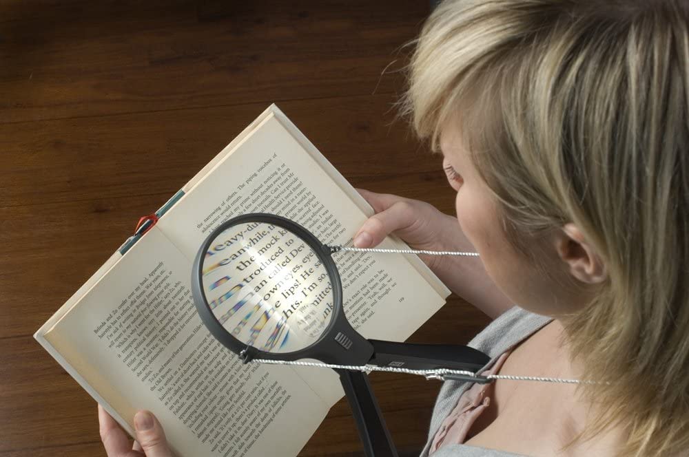 Donna anziana con ipovisione che utilizza una lente d’ingrandimento per leggere